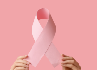 Breast Cancer Awareness Month ribbon being held up by many hands